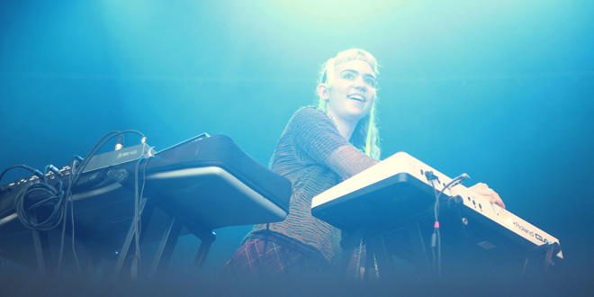 GRIMES IS SURROUNDED BY MANY KEYBOARDS TO DEVELOP NEW ATMOSPHERES AND IDEAS. 