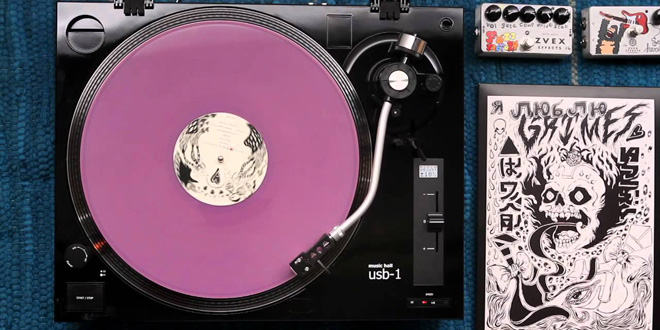 THE SPECTACULAR LIMITED EDITION LAVENDER VYNIL LP OF “VISIONS” (2012) ON A TURNTABLE. 